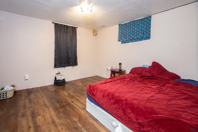 bedroom with a textured ceiling and wood finished floors