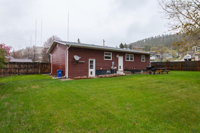 back of house featuring a lawn, a fenced backyard, and entry steps