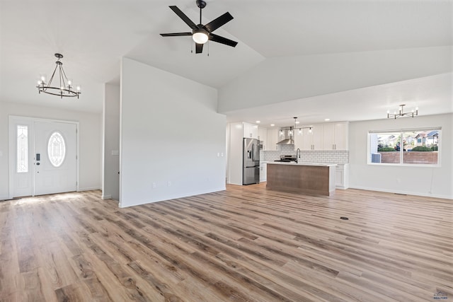 unfurnished living room featuring recessed lighting, light wood-style flooring, ceiling fan with notable chandelier, and high vaulted ceiling
