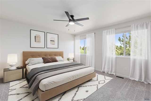 carpeted bedroom with baseboards, a ceiling fan, and visible vents