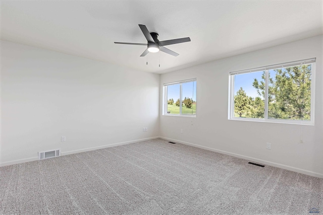 empty room with baseboards, ceiling fan, carpet flooring, and visible vents