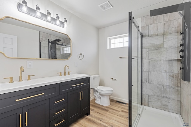 bathroom featuring wood finished floors, a sink, a stall shower, and toilet