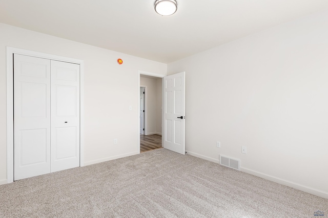 unfurnished bedroom featuring visible vents, carpet flooring, baseboards, and a closet