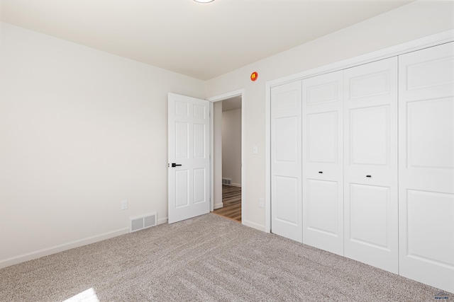 unfurnished bedroom with a closet, baseboards, carpet flooring, and visible vents