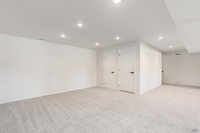 interior space featuring baseboards, light carpet, recessed lighting, and visible vents