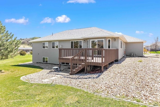 back of property with a wooden deck, cooling unit, roof with shingles, a patio area, and a lawn