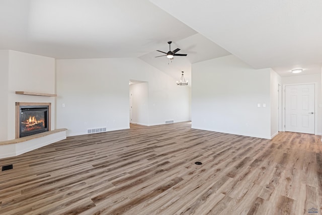 unfurnished living room with a ceiling fan, visible vents, vaulted ceiling, a glass covered fireplace, and light wood-style flooring