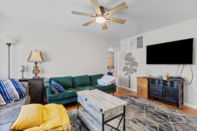 living area with baseboards, a ceiling fan, wood finished floors, and visible vents