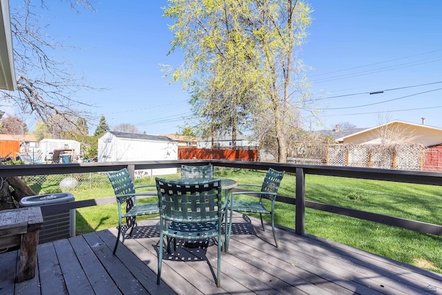deck featuring fence, outdoor dining area, a yard, and central AC