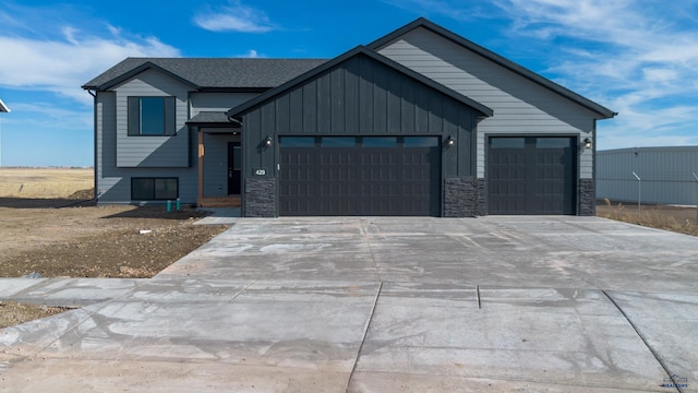 view of front of property with a garage, board and batten siding, concrete driveway, and stone siding