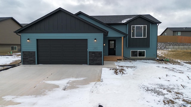 1241 Kenai Dr, Box Elder, SD 57719 - view of front of house with board and batten siding, an attached garage, concrete driveway, and stone siding