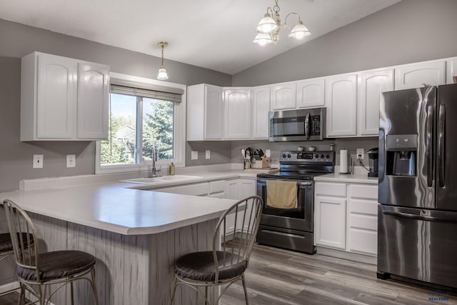 5235 Weathervane Ln, Rapid City, SD 57703 - kitchen with a peninsula, a kitchen bar, a sink, vaulted ceiling, and stainless steel appliances