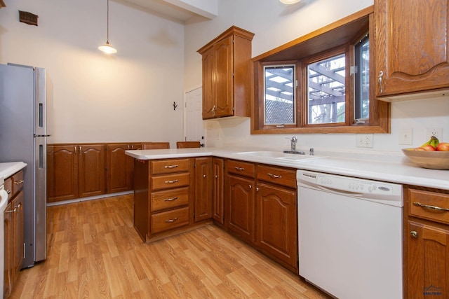 3005 Glenwood Dr, Rapid City, SD 57702 - kitchen featuring freestanding refrigerator, a peninsula, a sink, light wood-style flooring, and dishwasher