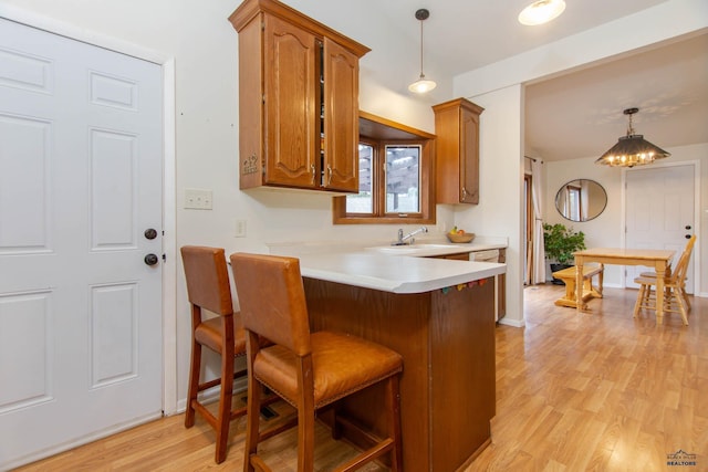 3005 Glenwood Dr, Rapid City, SD 57702 - kitchen featuring light countertops, brown cabinetry, decorative light fixtures, light wood-type flooring, and a kitchen bar