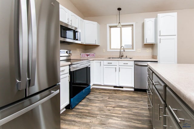 kitchen featuring dark wood-style floors, light countertops, white cabinets, a sink, and stainless steel appliances