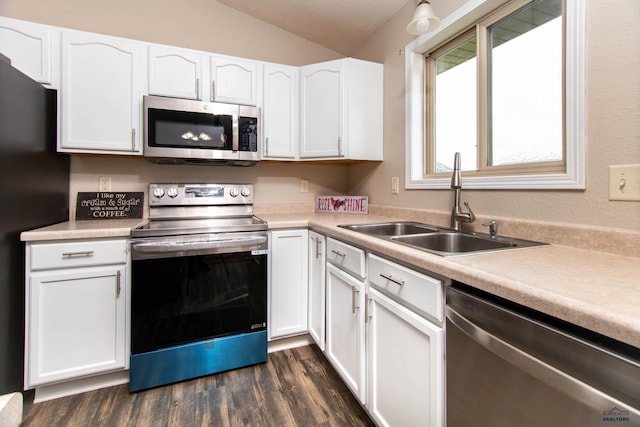 kitchen with a sink, white cabinetry, vaulted ceiling, and stainless steel appliances