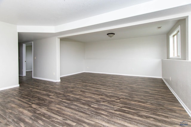 empty room featuring baseboards, dark wood finished floors, and visible vents