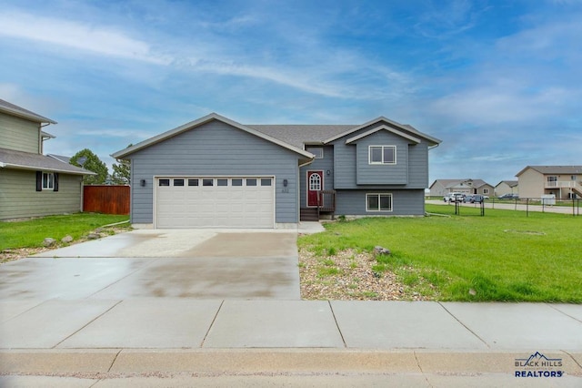 tri-level home with fence, concrete driveway, a front lawn, and a garage