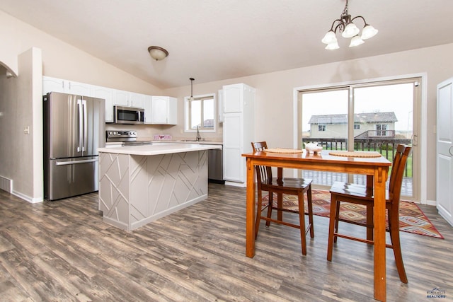 kitchen featuring lofted ceiling, a kitchen island, white cabinets, a sink, and stainless steel appliances