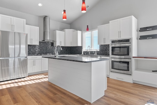 13416 Frontier Loop, Piedmont, SD 57769 - kitchen with wall chimney range hood, a sink, white cabinets, stainless steel appliances, and an island with sink
