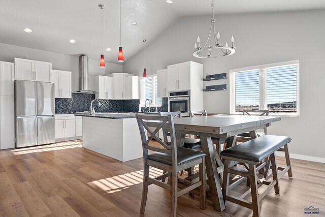 13416 Frontier Loop, Piedmont, SD 57769 - kitchen with decorative backsplash, dark countertops, high vaulted ceiling, wall chimney exhaust hood, and stainless steel appliances