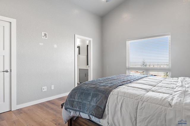 13416 Frontier Loop, Piedmont, SD 57769 - bedroom with connected bathroom, a textured wall, baseboards, wood finished floors, and lofted ceiling