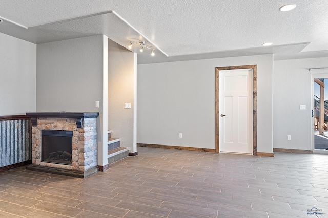 13416 Frontier Loop, Piedmont, SD 57769 - unfurnished living room with a textured ceiling, a fireplace, wood finished floors, and stairway