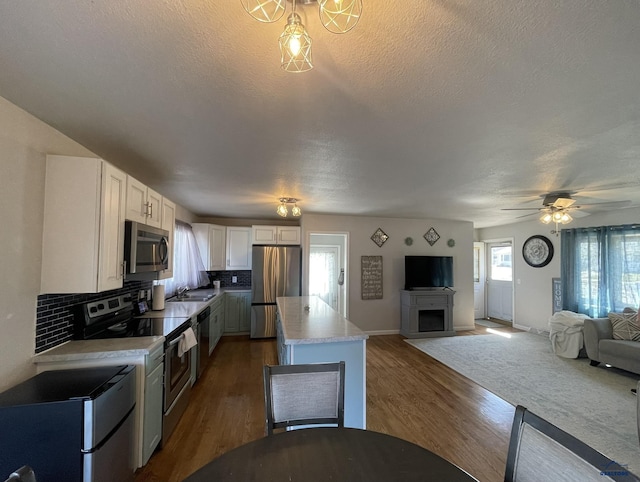 kitchen with a kitchen island, backsplash, dark wood-style flooring, white cabinets, and stainless steel appliances