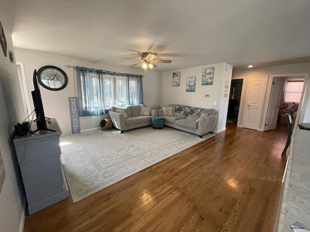 living room with baseboards, ceiling fan, and wood finished floors