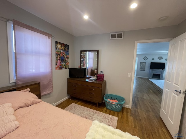 bedroom with baseboards, a fireplace, dark wood finished floors, and visible vents