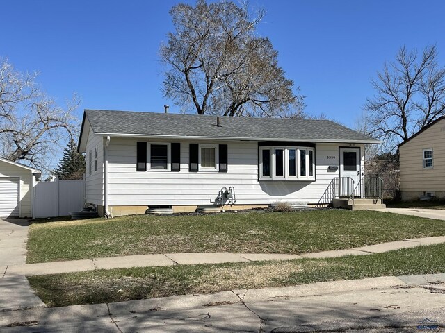 view of front facade with fence, a shingled roof, and a front yard