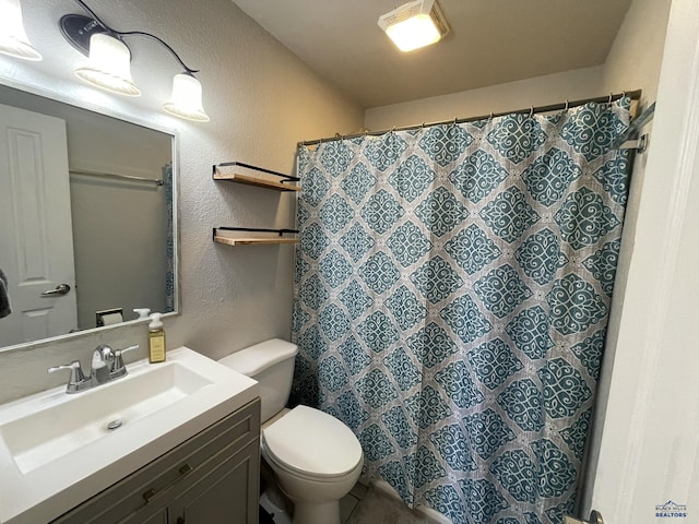 bathroom with vanity, a textured wall, toilet, and curtained shower
