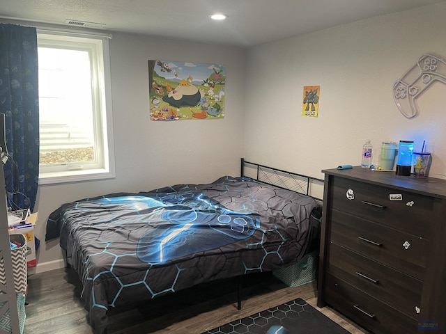 bedroom featuring wood finished floors and visible vents