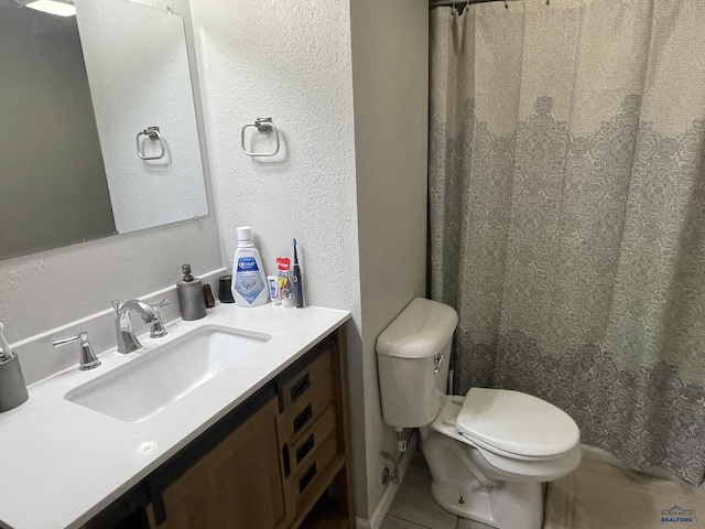 bathroom with vanity, a textured wall, tile patterned flooring, and toilet