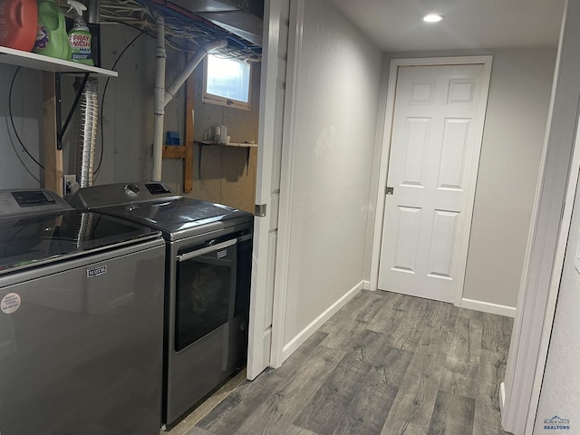 laundry area with laundry area, baseboards, wood finished floors, and washing machine and clothes dryer