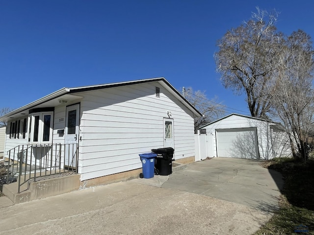 view of side of property with concrete driveway, an outdoor structure, and a detached garage