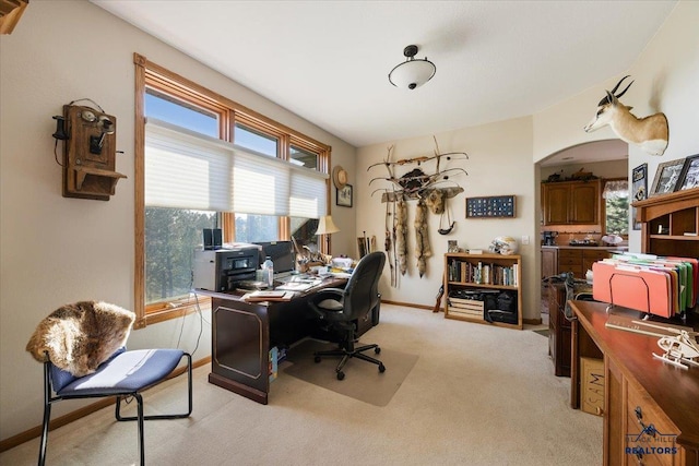 office featuring arched walkways, baseboards, and light colored carpet
