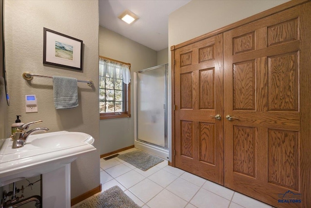 full bath featuring baseboards, tile patterned flooring, and a stall shower
