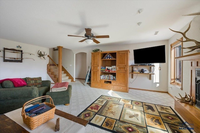 living room featuring arched walkways, stairs, a ceiling fan, and light carpet