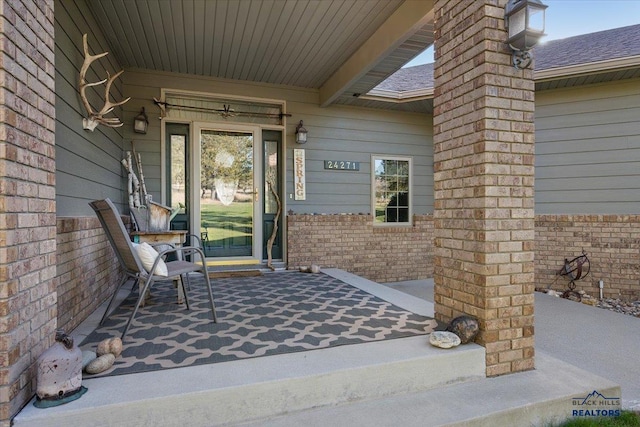 entrance to property featuring a porch and brick siding