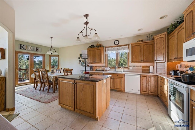 kitchen featuring white appliances, light tile patterned floors, plenty of natural light, and a sink