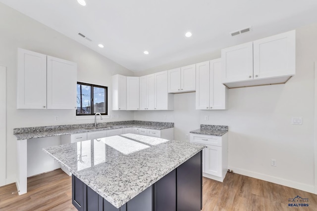 3226 W Rapid, Rapid City, SD 57702 - kitchen with light stone counters, a sink, white cabinetry, lofted ceiling, and visible vents