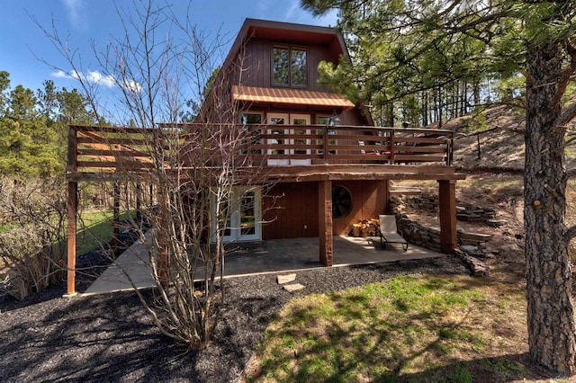 rear view of house with french doors, a wooden deck, and a patio area