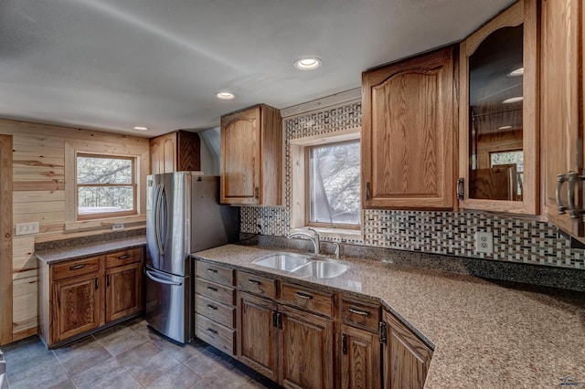 kitchen featuring glass insert cabinets, brown cabinetry, decorative backsplash, and a sink