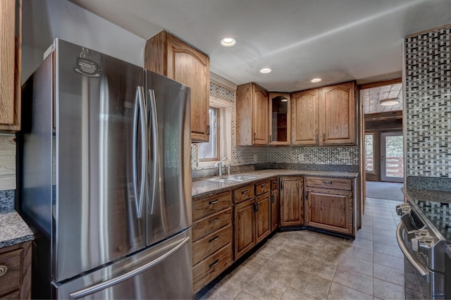 kitchen featuring brown cabinetry, glass insert cabinets, recessed lighting, a sink, and stainless steel appliances