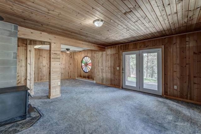 unfurnished living room featuring carpet, baseboard heating, a wood stove, and wood walls
