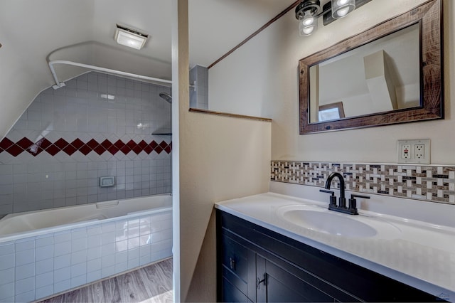 full bathroom with tasteful backsplash, vanity, tiled shower / bath, and wood finished floors