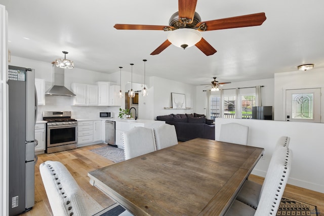 dining room featuring light wood-type flooring and ceiling fan with notable chandelier
