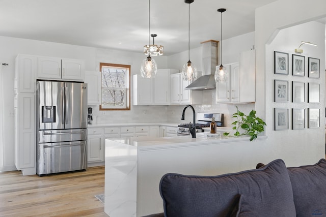 kitchen with white cabinets, stainless steel appliances, and wall chimney exhaust hood