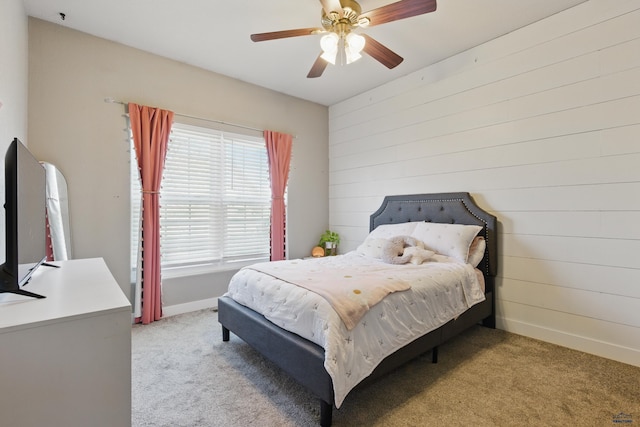 bedroom with ceiling fan, wood walls, light colored carpet, and baseboards